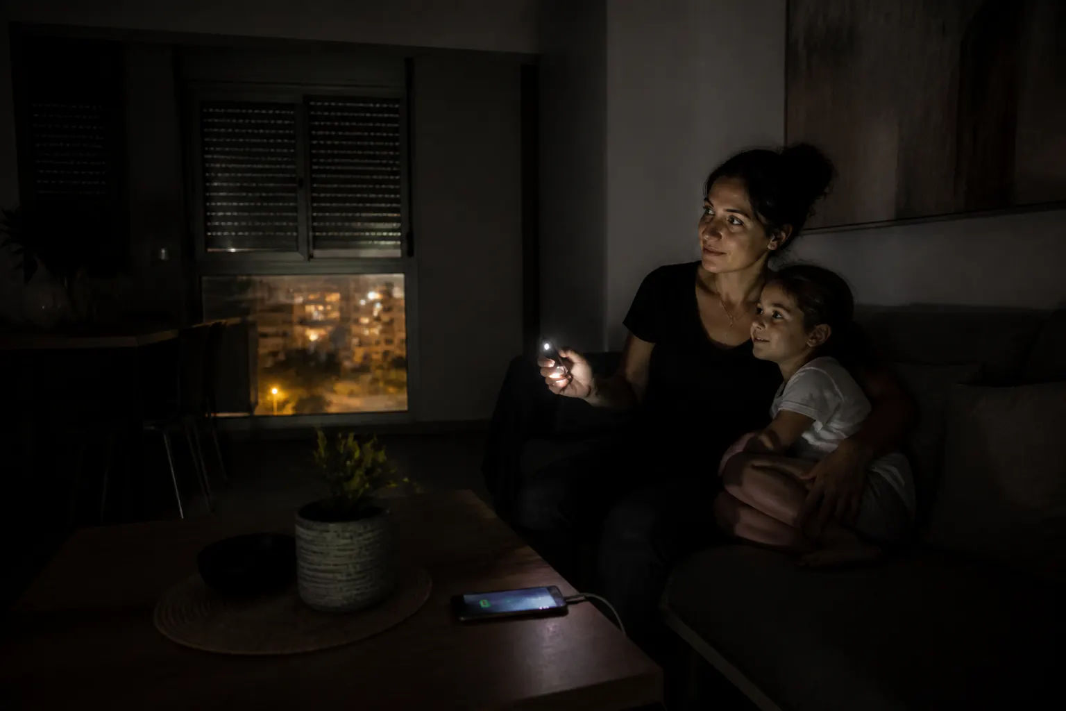 משפחה בחדר מוגן עם אור ומטען שעובד בהפסקת חשמל